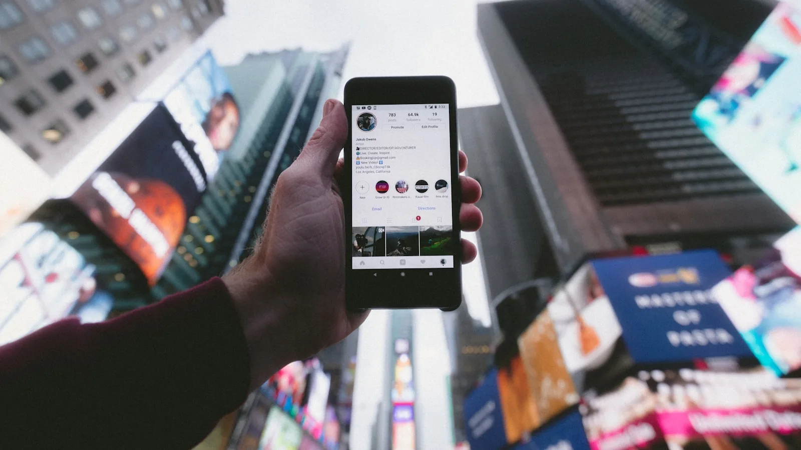 Persona sosteniendo un teléfono móvil mientras explora aplicaciones en la ciudad