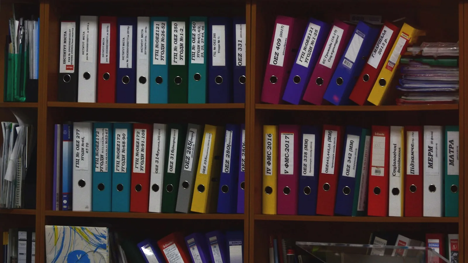 Archivadores de colores ordenados en estanterías, como archivos bien guardados