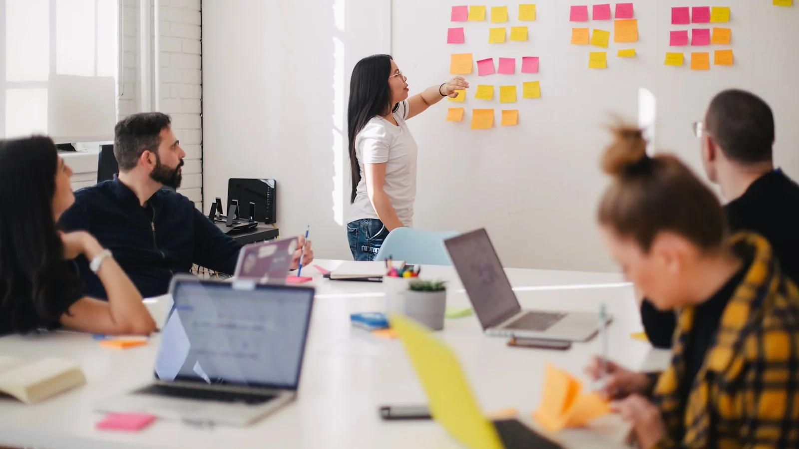 Persona dirigiendo una reunión de equipo con notas adhesivas en la pared