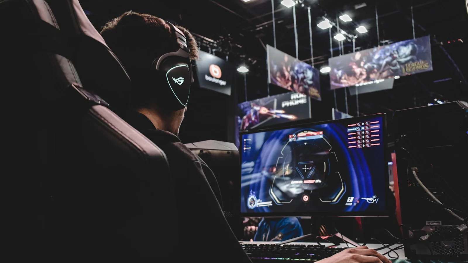Jugador con auriculares frente a varias pantallas en un evento de videojuegos